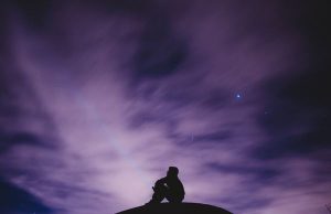 alt="image showing man alone on a hill at night"